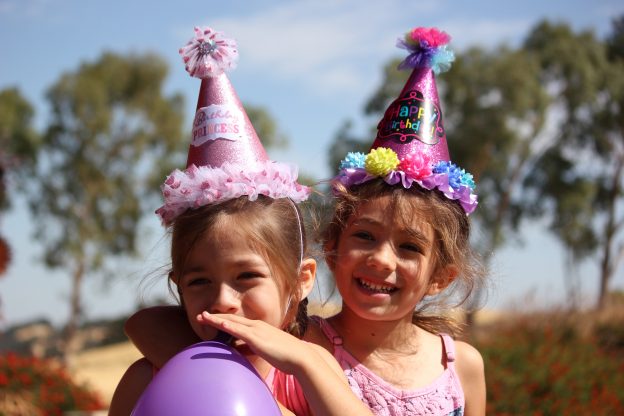 Two children with party hats and balloons